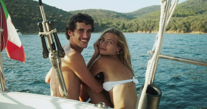 Beautiful smiling young couple kissing on a sailboat in the Ligurian Sea.
