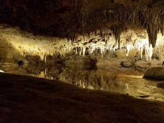 brown stalactites and stalagmites in cave or cavern with water