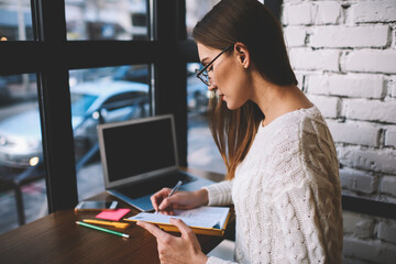 Young freelancer planning work on week writing down all details of organization issues in notebook