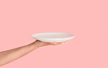 Millennial woman holding empty plate on pink background, mockup for design