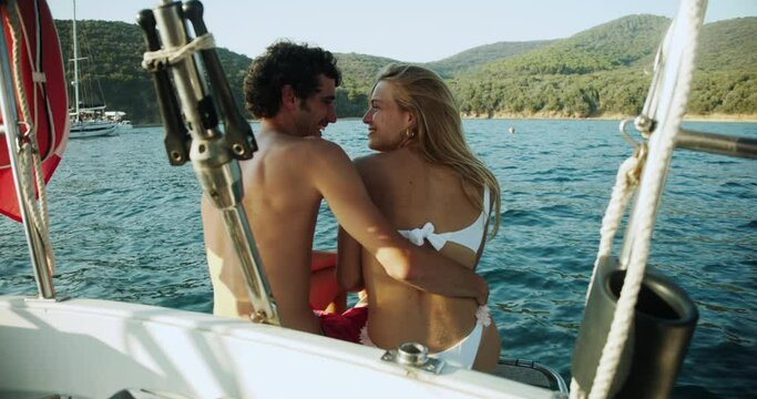 Beautiful smiling young couple kissing on a sailboat in the Ligurian Sea.
