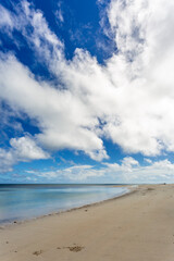 Deserted beach and white puffy clouds in blue sky