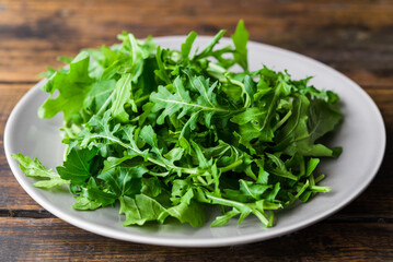 Arugula rocket salad on a plate against wooden background