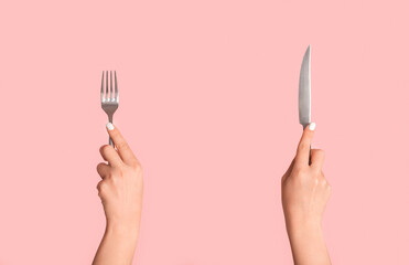 Cropped view of girl hands holding metal knife and fork on pink background