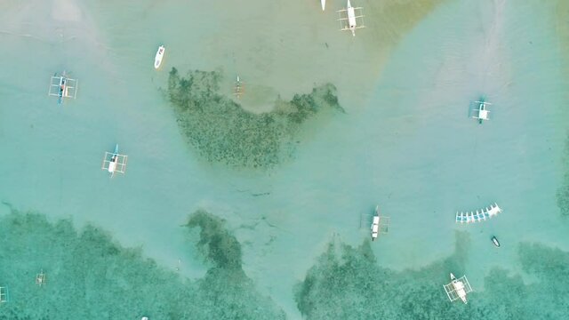 Top drone view of a traditional philippine boats on the surface of the azure water in the lagoon. Seascape with blue bay and boats. El Nido, Port Barton, Palawan. Summer and travel vacation concept.