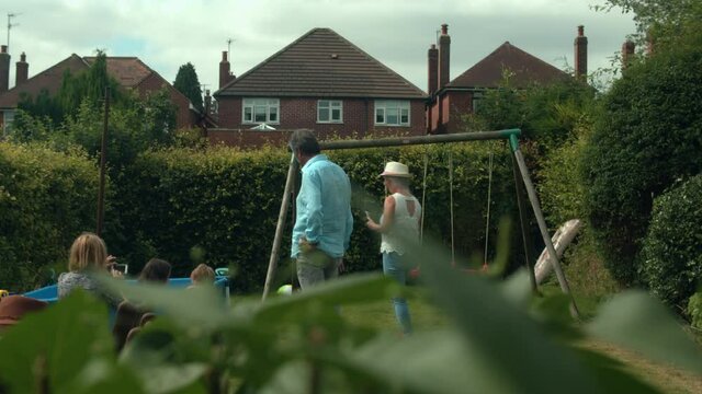 Family group in a garden with paddling pool and wing.