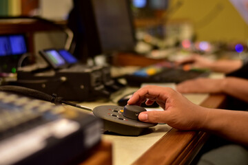 Closeup of sound engineer's hand moving sliders on audio mixing board.