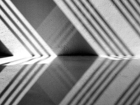 Abstract light and shadow of the wrought iron reflects on the concrete wall and tile floor in the room.