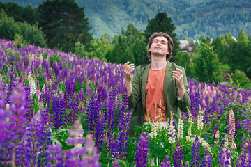 Tall handsome man standing on lupine flowers field