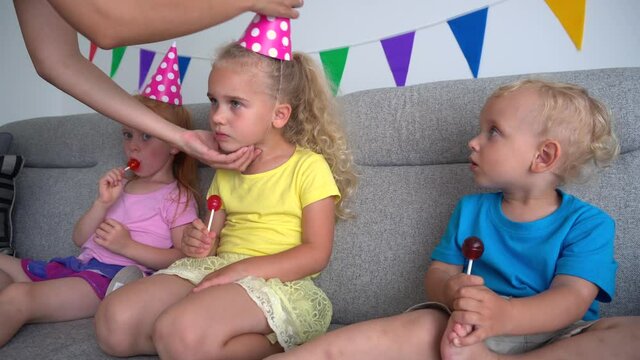 Mother hands put on party hats on children heads. birthday party. camera motion