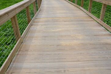 Fototapeta na wymiar wooden boardwalk or trail with railing and green plants