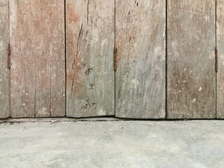 Hinged old wooden house door and cement floor. Closeup bottom side.