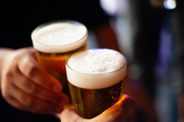 Cheers! Clink glasses. Close-up shots of hands holding beer glasses and beer bubbles.