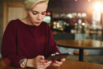 Caucasian millennial female teenager using tablet in coffee shop