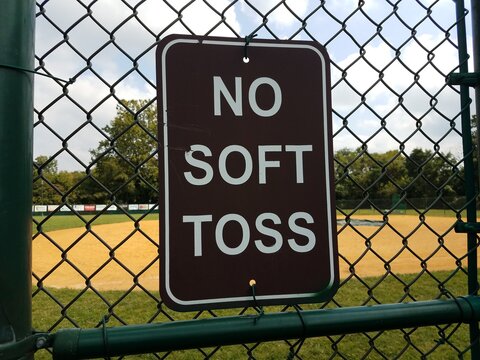 Black No Soft Toss Sign On Metal Fence At Baseball Field