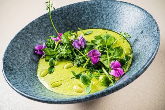 green pea cream soup with edible flowers