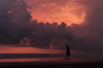 social distancing on the beach , pink and orange amazing cloudy sky , beautiful sunset , Bali Indonesia , solo outdoor walking 