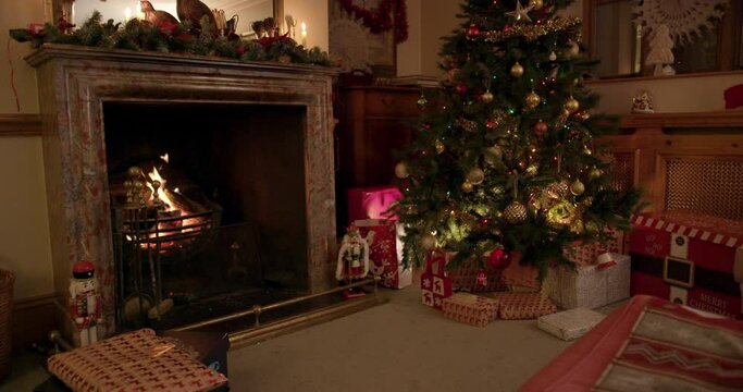 MS Christmas tree with gifts near fireplace in living room / Dinton, Wiltshire, UK