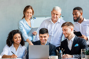 Smiling Coworkers Working Together On One Laptop In Modern Office