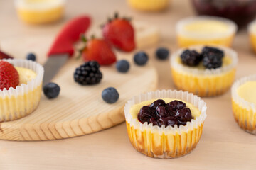 Mini cheesecake with blueberry, blackberry and strawberry ready to be served on wooden table