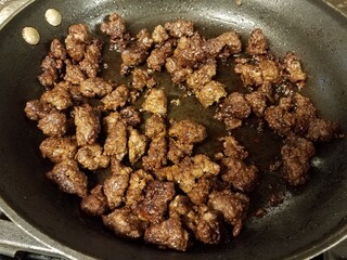 ground beef cooking in frying pan with oil