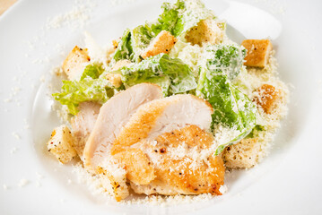 Fresh caesar salad in white plate, wooden background