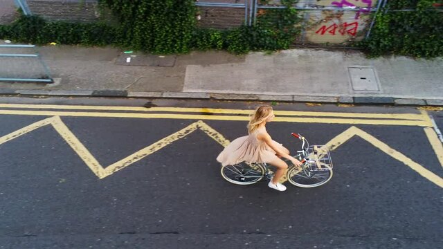 WS HA TS Young woman cycling on road / London, UK
