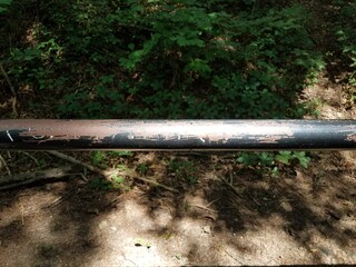 black metal bar in the woods with graffiti scratched out