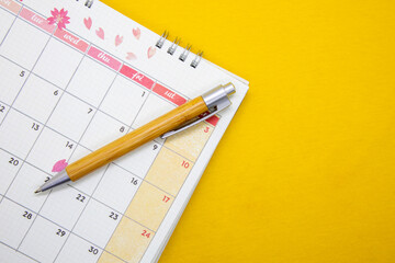 Close up of calendar on yellow background, the pen is on it  for business planning or travel planning concept.