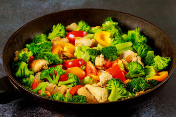 Asian dish chicken with paprika and broccoli in wok.