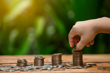 Coins a men's hand placed and sorted coins on a wooden board.