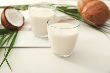 Glasses of tasty coconut milk on white background