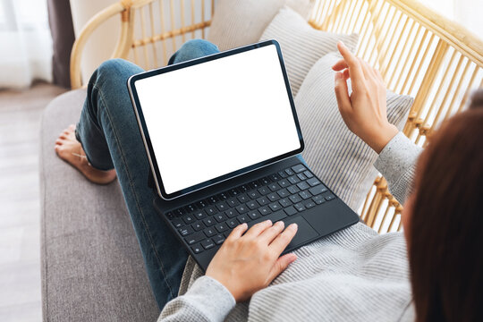 Top view mockup image of a woman using black tablet pc with blank desktop white screen as a computer pc while lying on a sofa at home