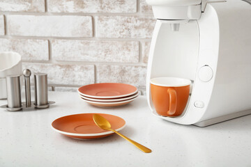 Coffee machine with cup and saucers on table in kitchen