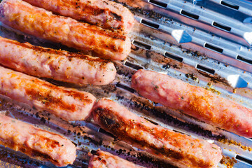 Sausages meat grilling on gas grill