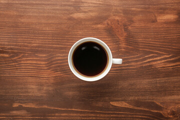 Cup of hot coffee on wooden background, top view