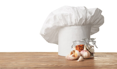 Chef's hat and spices on table against white background