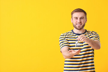 Happy young man with key on color background