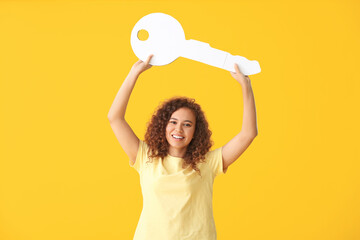 Fototapeta na wymiar Young woman with big paper key on color background