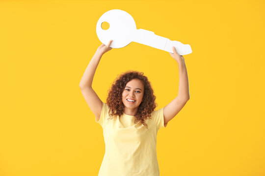 Young woman with big paper key on color background