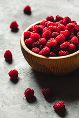 raspberries in wood bowl on gray table, vintage