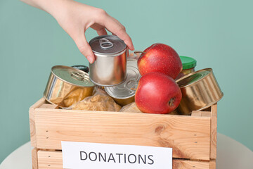 Woman putting donations in box on table