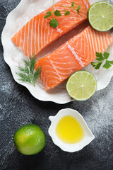 Raw fresh salmon fillet on ice with seasonings, above view on a dark-grey stone background, vertical shot