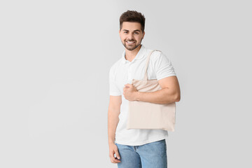 Young man with eco bag on light background