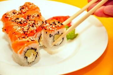 Colorful Sushi on white plate. Red sushi roll with rice salmon fish sesame black & white seeds wasabi sauce man eating in sushi bar. Sushi menu. Japanese delicious nigiri fish food. Seafood restaurant