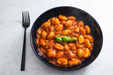 plant-based food, potato gnocchi with red pesto sauce and basil on top