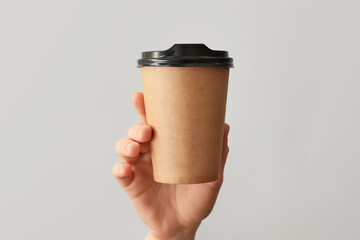 Female hand with cup of coffee on grey background
