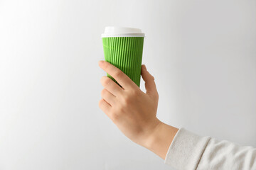 Female hand with cup of coffee on grey background