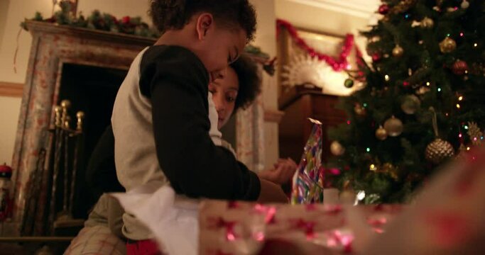 MS HANDHELD Happy mother and son (6-7) opening gift and hugging / Dinton, Wiltshire, UK