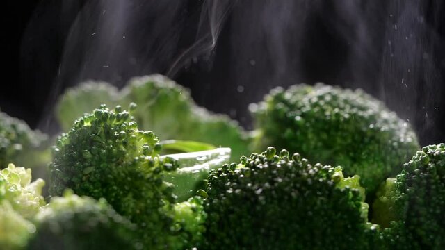 Close-up of boiling broccoli with steam in slow motion. Cocking broccoli on dark background